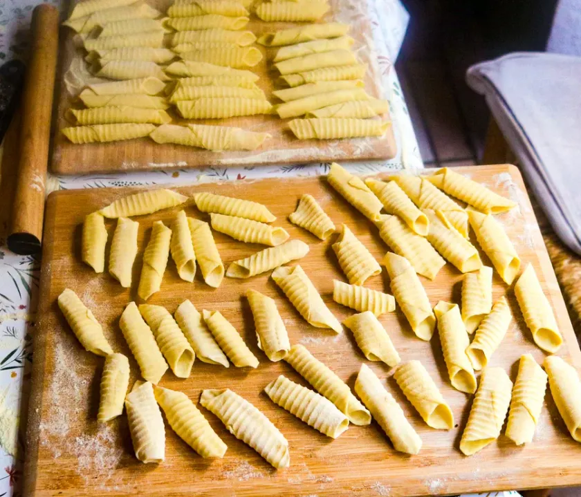 Frisch gerollte handgemachte Garganelli auf bemehlten Holzbrettern